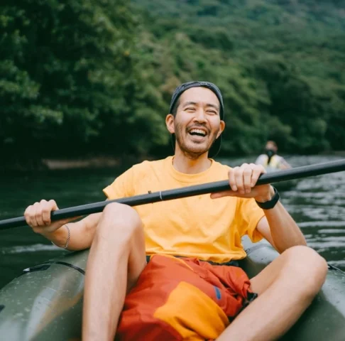 Photo of smiling young man paddling a boat