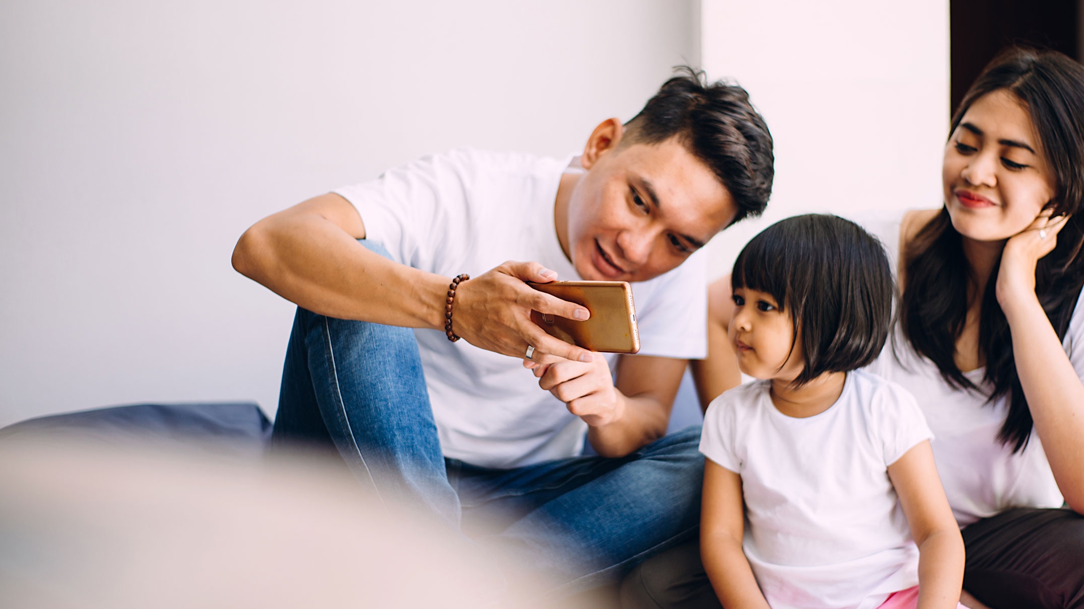 Image of a young family looking at a mobile phone screen